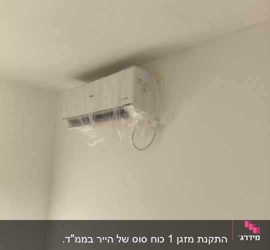 מזגן מותקן על קיר עם כיסוי פלסטיק